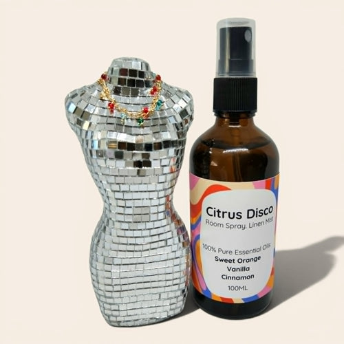 Bottle of Citrus Disco room spray next to a disco ball on a beige background
