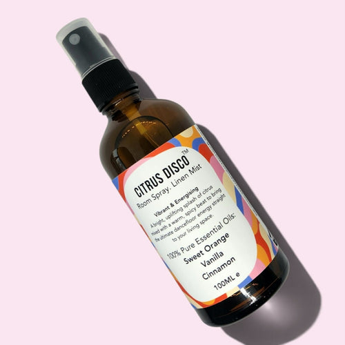 Amber glass bottle of Citrus Disco Room Spray with a light pink background