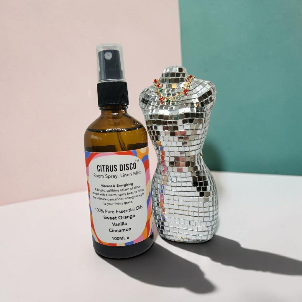 Amber glass bottle of Citrus Disco room spray sits in a studio with a glitter prop