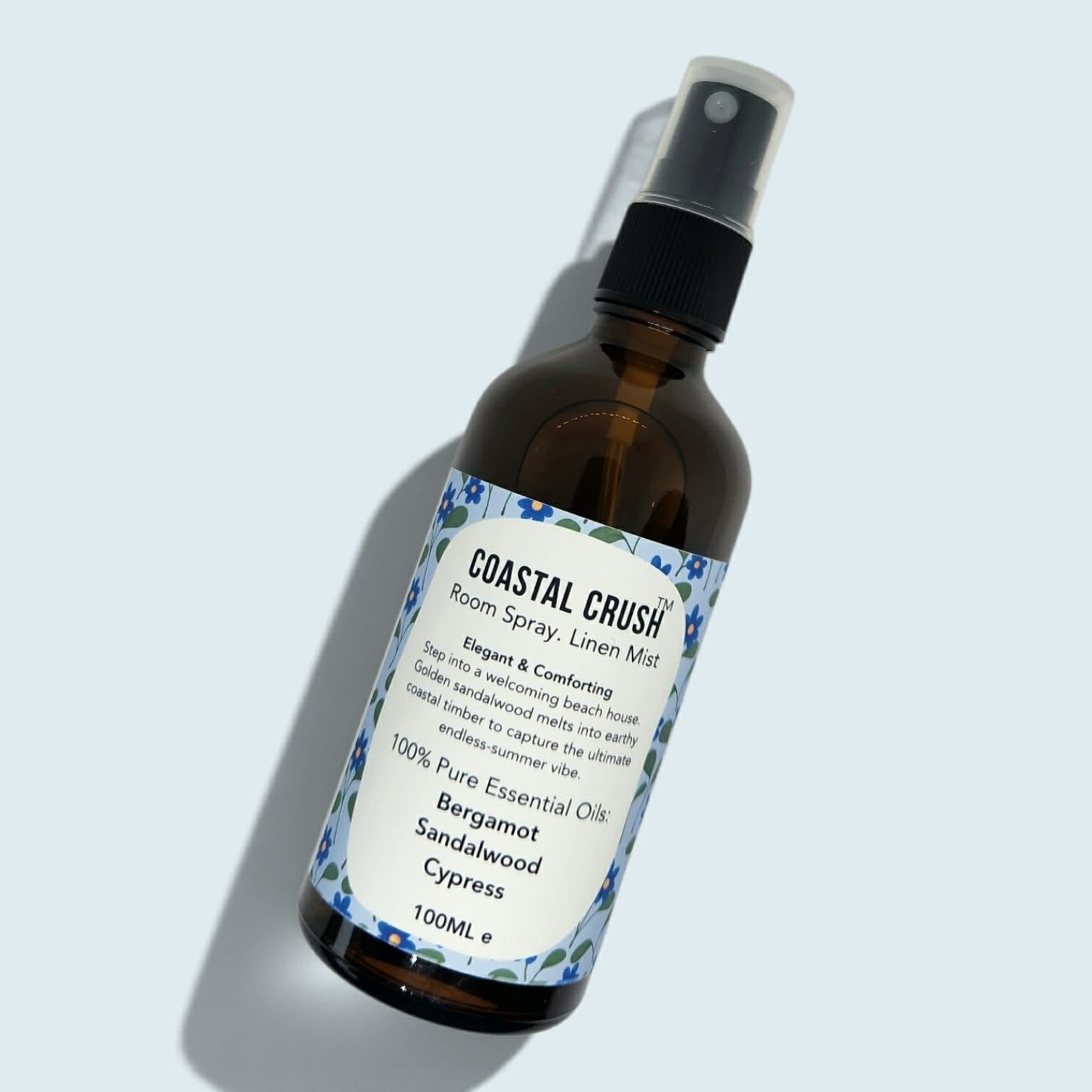 Amber glass bottle of Coastal Crush Room Spray set in a light blue background 