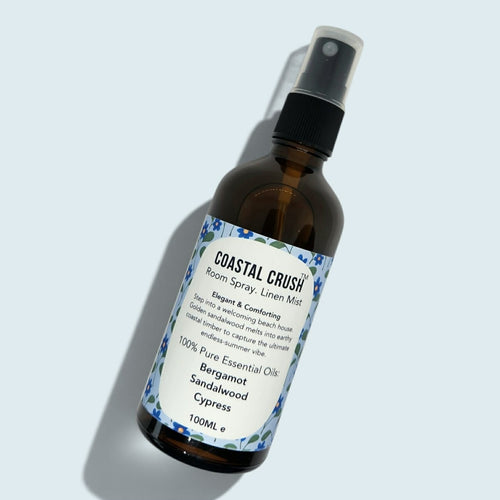 Amber glass bottle of Coastal Crush Room Spray set in a light blue background 