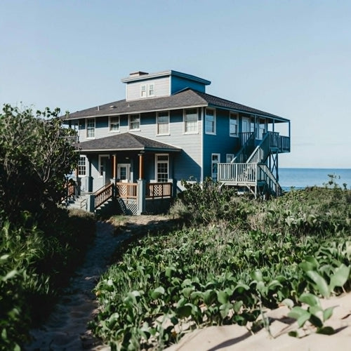 Blue beach house with a staircase leading down to the sand