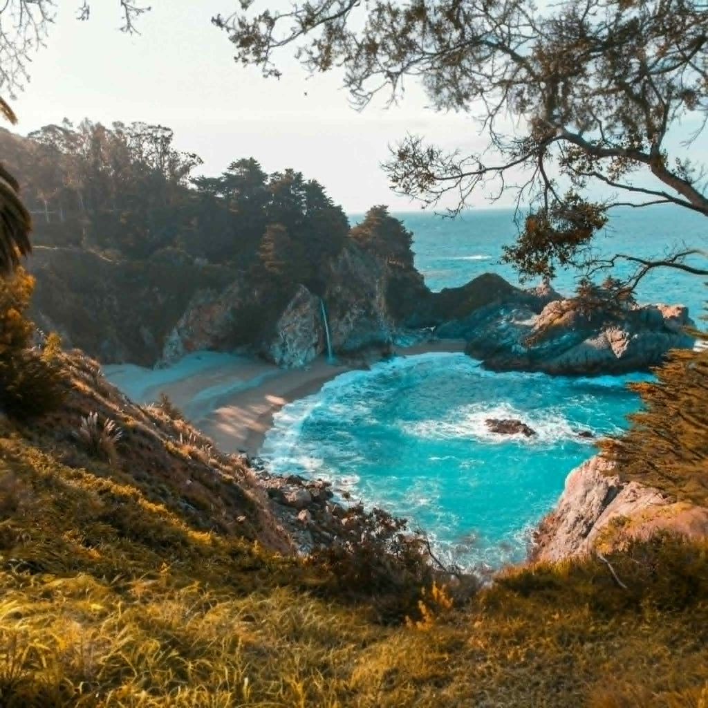 Coastal landscape with turquoise waters, rocky cliffs, and greenery.