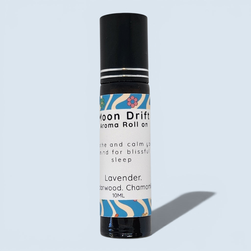 A 10ml roll-on bottle of Moon Drift Lavender aroma roll on, featuring a black cap and a white label with blue and pink floral patterns, set against a light blue background.